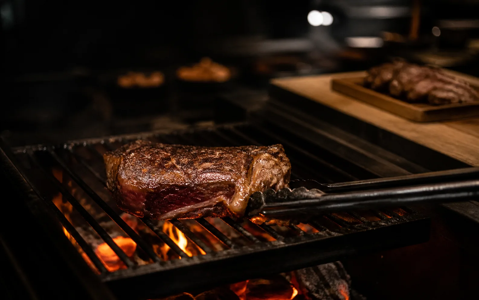 Concept preview of dry-aged steak searing over charcoal in a professional kitchen